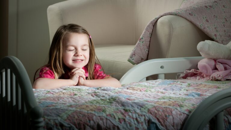 Young girl praying peacefully before bed in a cozy room.